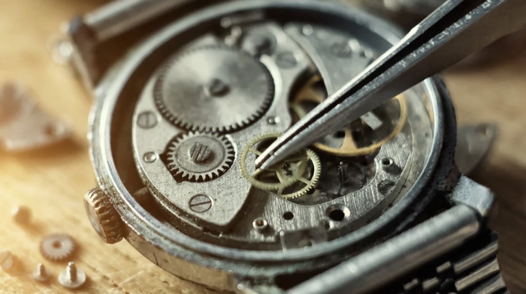 Mechanikus óra szerkezete, precíziós szerelés csipesszel; az óramű-univerzum metaforához